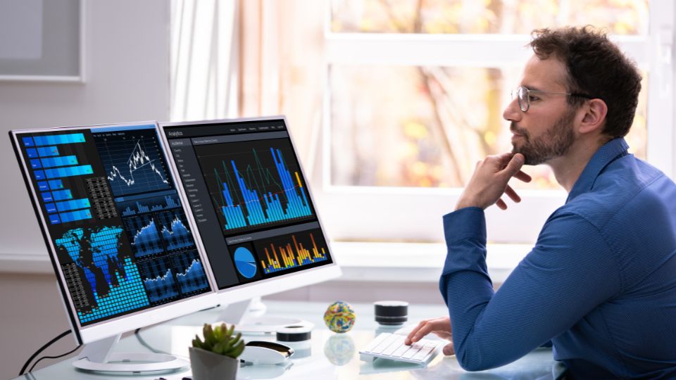 A Man Thoughtfully Analyzing Data On A Computer Screen